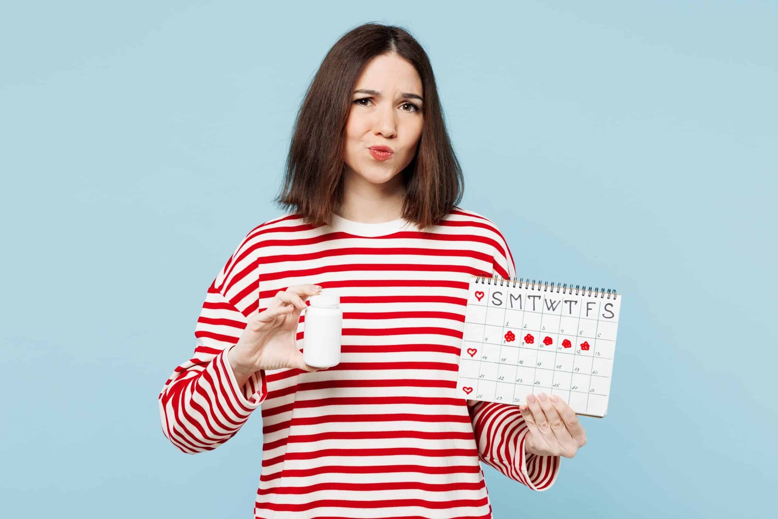 Frau hält eine Tablettendose und einen Kalender mit markierten Zyklustagen